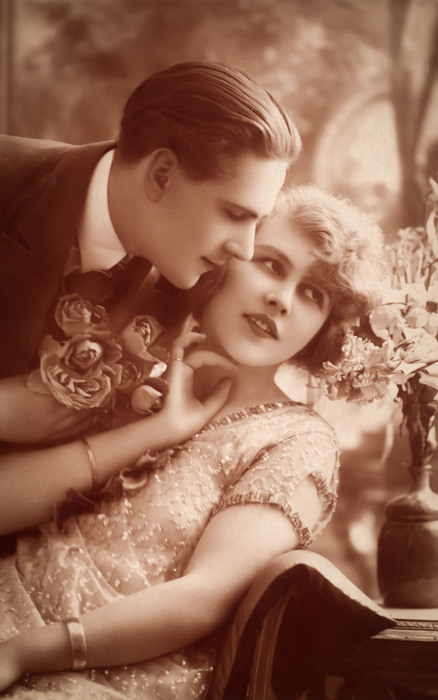 Anne et Marcel – La rose et le regard Marcel s'approche d'Anne pour lui offrir un bouquet de roses. Cette carte postale ancienne célébre le romantisme des Années folles.