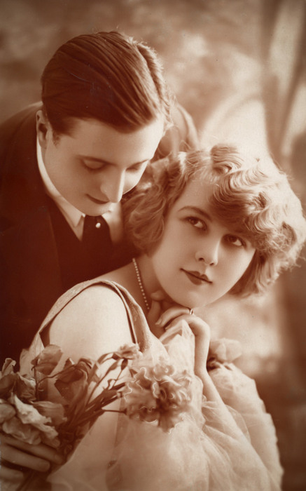 Anne et Robert - Tendresse partagée Dans cette photographie des Années folles, Robert se penchent sur Anne. Les fleurs et les regards soulignent la délicatesse de leurs sentiments.