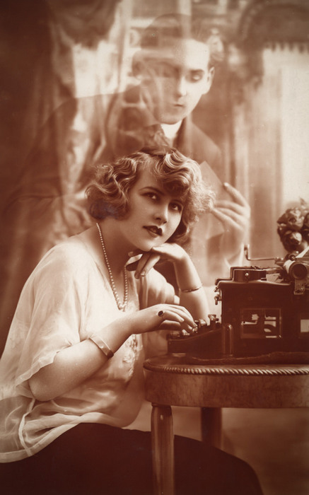 Anne et la lettre d'amour – Photomontage romantique vers 1920 Dans cette carte postale des années 1920, une jeune femme écrit à la machine, tandis que le visage de son amoureux apparaît en transparence derrière elle. Le subtil jeu de superposition et de transparence révèle toute la virtuosité du photomontage à cette époque.