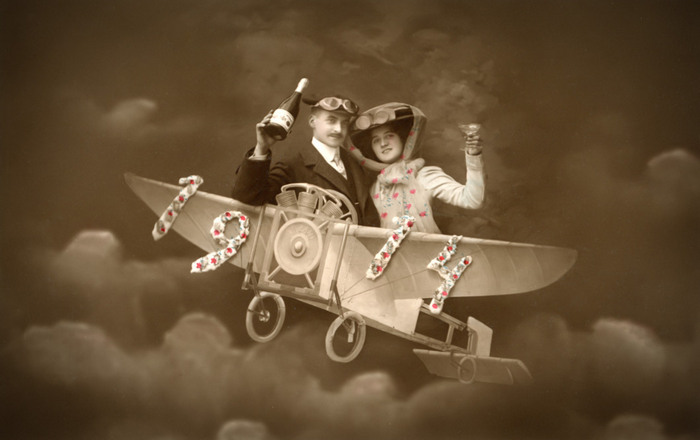 Albertine et Alphonse – L'envol à deux Albertine et Alphonse prennent place dans un petit aéroplane reconstitué en studio, Alphonse brandissant une bouteille de champagne. Cette carte postale photographique mêle le rêve d’aviation à l’imaginaire de la fête et du voyage au début du XXᵉ siècle.