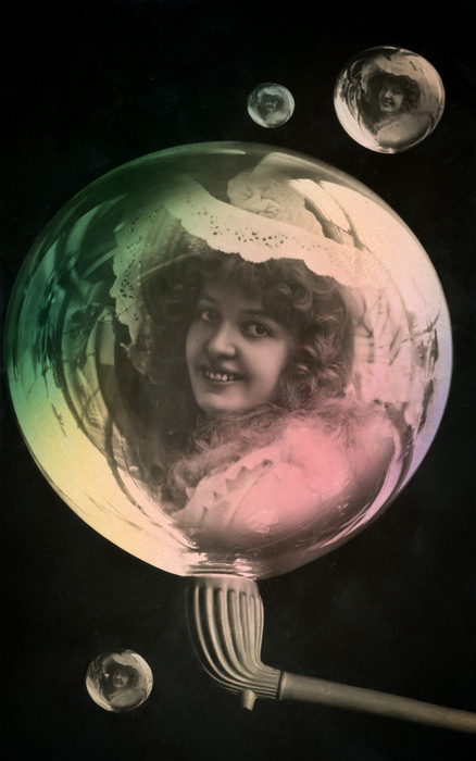 La bulle de savon – Portrait vers 1900 Dans cette carte postale de la Belle Époque, un portrait féminin apparaît au cœur d’une immense bulle de savon, entourée de bulles plus petites. Les effets de transparence et la délicate colorisation accentuent l’illusion d’un portrait suspendu dans une matière légère et fragile.