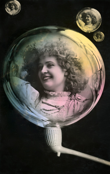 La bulle de savon – Portrait souriant vers 1900 Dans cette carte postale de la Belle Époque, une jeune femme souriante apparaît au cœur d’une grande bulle de savon, accompagnée de trois petits portraits. Les reflets colorés et les effets de transparence donnent à cette composition un étonnant effet de profondeur.