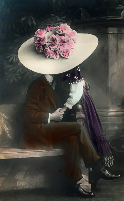 Edmonde et Lucien – Le baiser caché sous le chapeau Sous un immense chapeau orné de roses, Edmonde et Lucien échangent un baiser Cette carte postale photographique colorisée de la Belle Époque joue avec la pudeur et la suggestion.