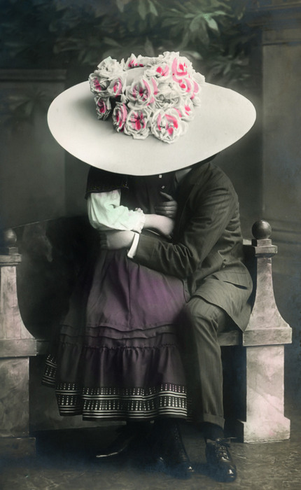 Edmonde et Lucien – L'étreinte cachée Dans cette carte postale photographique de la Belle Époque, le grand chapeau fleuri d'Edmonde masque le baiser qu'elle donne à Lucien.