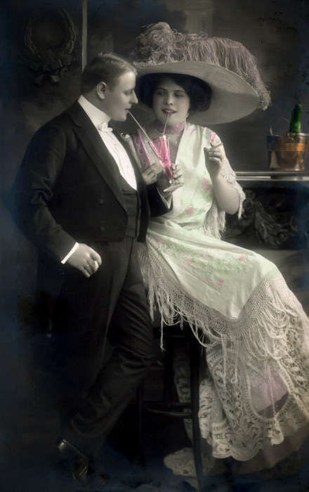 Élise et Auguste – Le grand chapeau Élise porte une robe aux longues franges et un imposant chapeau fleuri tandis qu'Auguste se tient à ses côtés en costume de ville. Ce portrait de couple témoigne du raffinement vestimentaire du début du XXᵉ siècle.