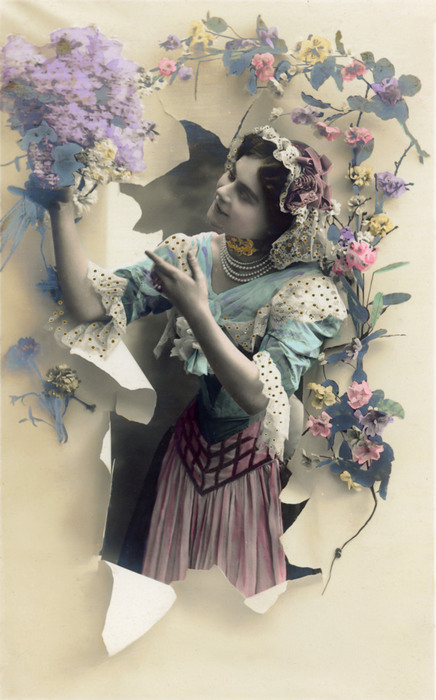 Émilienne parmi les fleurs – Papier déchiré vers 1900 Dans cette carte postale ancienne, Émilienne apparaît à travers une feuille de papier déchirée tandis qu’elle contemple un bouquet de fleurs. Les fines fleurs qui entourent son portrait renforcent l’illusion de profondeur et créent une composition particulièrement délicate.