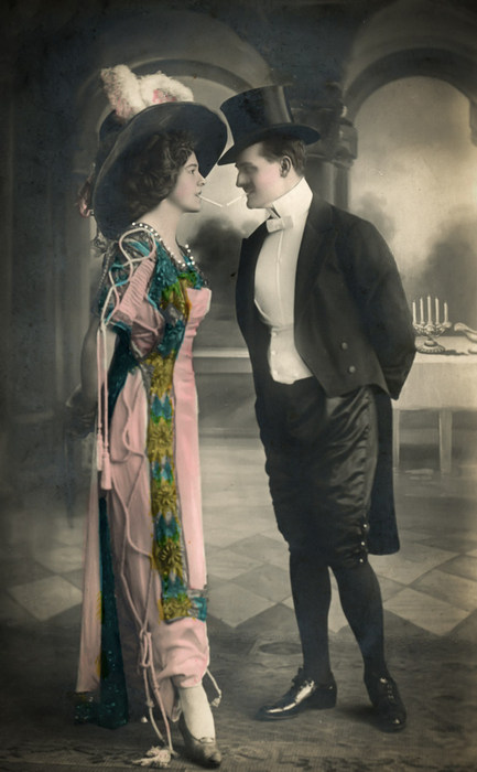Emma et Ernest – Une soirée toute en élégance Emma porte une longue robe élégante et un grand chapeau tandis qu'Ernest est vêtu d'un costume de soirée. Cette photographie ancienne évoque la mode raffinée de la Belle Époque.