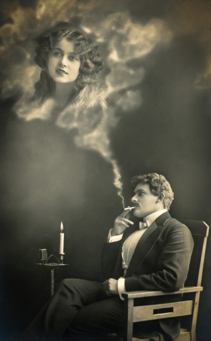 L'Absente rêvée d'Ernest – Scène 4 Dans cette carte postale ancienne, Ernest rêve à la femme qu’il aime et le visage de celle-ci se dessine dans la fumée de sa cigarette. Le photomontage et les effets de transparence donnent à cette apparition un caractère presque irréel.