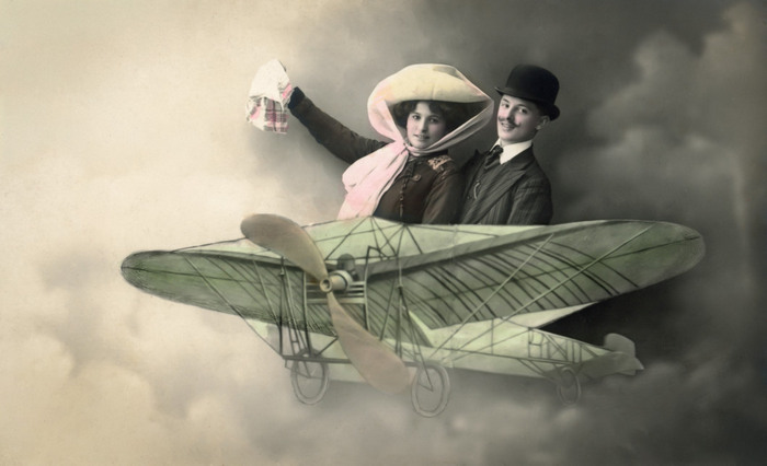 Ernestine et Clotaire – Premier envol Ernestine et Clotaire prennent place à bord d’un aéroplane reconstitué en studio. Cette carte postale photographique témoigne de la fascination pour l’aviation et du rêve de voyage au début du XXᵉ siècle.
