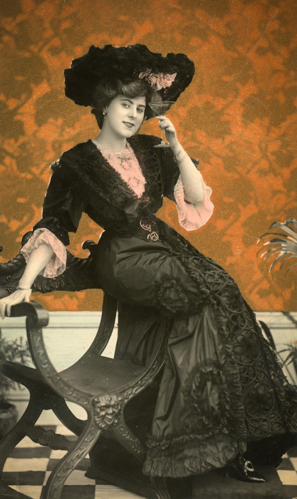 Irma à la robe noire élégante Assise sur un banc, Irma est vêtue d'une longue robe noire cintrée et est coiffée d'un large chapeau garni de dentelle. Ce portrait photographique illustre l'élégance de la mode féminine de la Belle Époque.