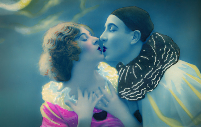 Le baiser de Pierrot et Colombine Dans cette carte postale ancienne colorisée des Années folles, Jeanne et Lucien, vêtus des costumes de Pierrot et Colombine, échangent un baiser.