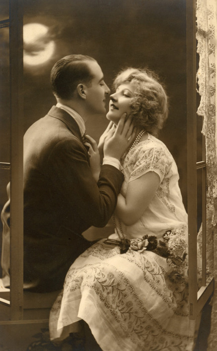 Josette et Alphonse – Clair de lune à la fenêtre Dans cette carte postale romantique des Années folles, Josette et Alphonse échangent un regard langoureux près d'une fenêtre éclairée par la lune.