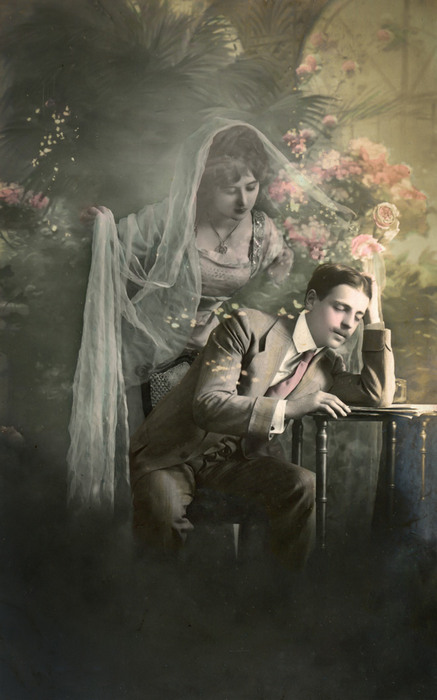 Léon et l'Absente rêvée – Apparition romantique Dans cette carte postale de la Belle Époque, Léon songe, tandis qu’une femme apparaît derrière lui dans un voile de brume. Le photomontage et les effets de transparence donnent à cette apparition une présence presque irréelle.