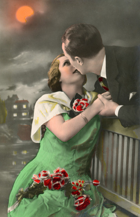 Lucienne et Rolland – Un baiser sur le banc Assise sur un banc sous une lune rougeoyante, Lucienne se tourne vers Roland qui s’approche pour l’embrasser. La lumière de la lune et les teintes colorisées accentuent l’atmosphère intime de cette scène des Années folles.