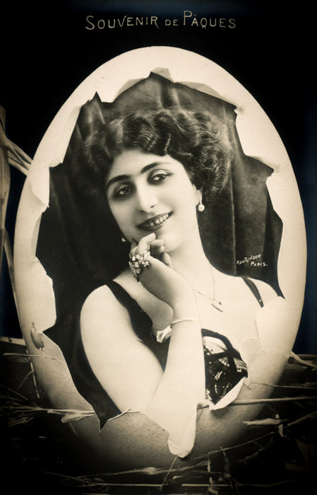 L'œuf de Pâques – Souvenir de Pâques vers 1900 Dans cette carte postale de la Belle Époque, Lina Cavalieri apparaît au cœur d’un œuf de Pâques, dans une composition réalisée par les studios Reutlinger. Son sourire et sa pose délicate apportent à cette création une atmosphère particulièrement raffinée.