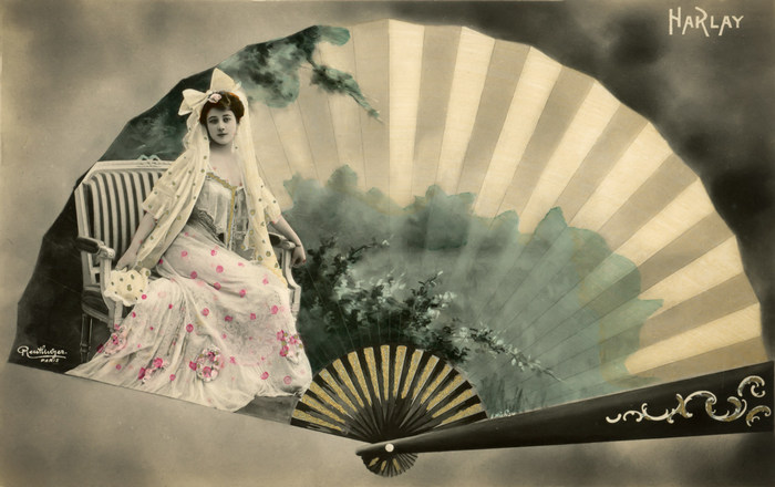 L'éventail – Harlay vers 1900 Dans cette carte postale de la Belle Époque, Harlay apparaît au cœur d’un éventail largement déployé, entourée d’un décor paysager. Le jeu de composition associe portrait photographique, illustration et motifs décoratifs pour créer une étonnante illusion visuelle.