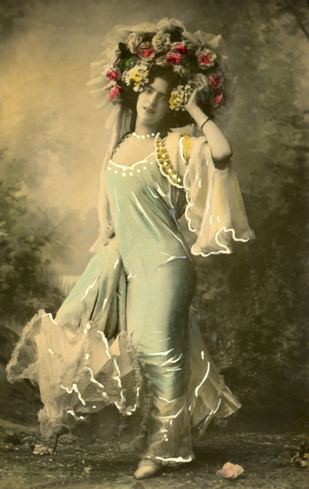 Olga – La danseuse en fleurs Olga porte une robe drapée aux voiles légers et est coiffée d'une couronne de fleurs impressionnante. Cette photographie ancienne évoque l'élégance des costumes des artistes de la Belle Époque.