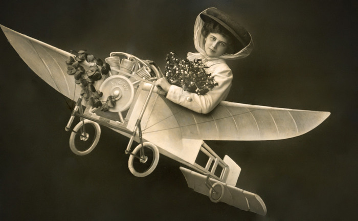 Rachel – Au-dessus des nuages Rachel prend place dans un petit aéroplane reconstitué en studio. Cette carte postale photographique donne vie au rêve d’aviation qui fascine les contemporains au début du XXᵉ siècle.