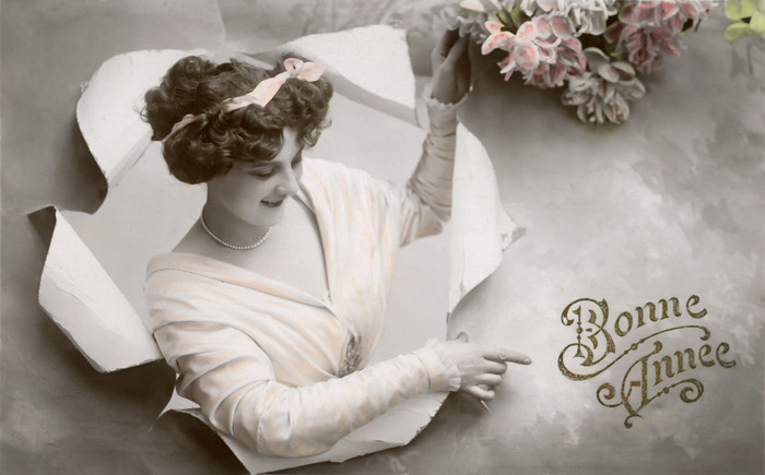 Victorine souhaite la Bonne Année – Papier déchiré Belle Époque Dans cette carte postale ancienne, Victorine surgit d’une feuille de papier déchirée tout en désignant l’inscription « Bonne Année ». Le jeu de découpe et de relief crée une étonnante illusion de profondeur.