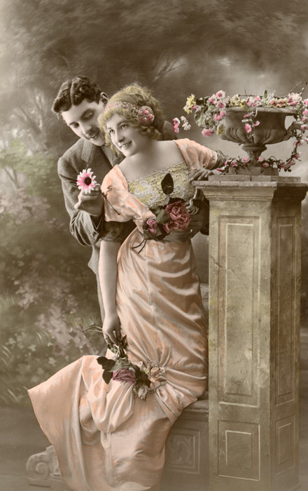 Elsa et Marius au jardin | Décor peint Elsa et Marius prennent place dans un jardin romantique reconstitué en studio. Les fleurs, la vasque et les attitudes des deux personnages composent une scène galante aux accents bucoliques.