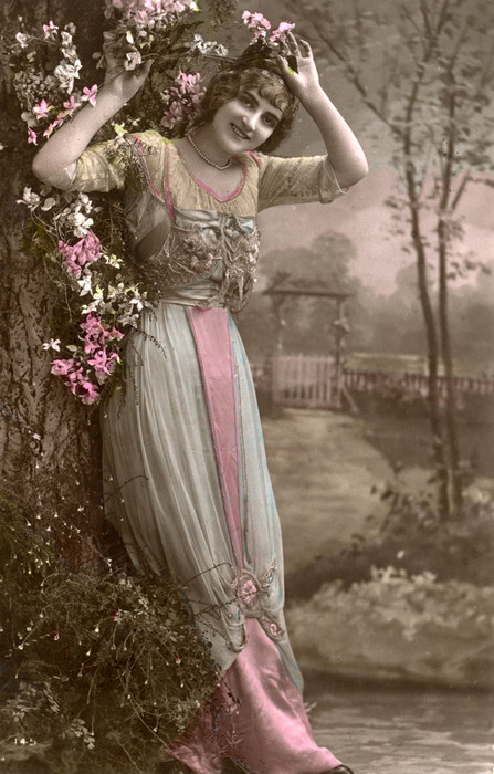Ernestine au jardin fleuri | Décor peint Ernestine pose devant un jardin fleuri peint en studio. La composition florale et les teintes délicatement colorisées créent une atmosphère champêtre.