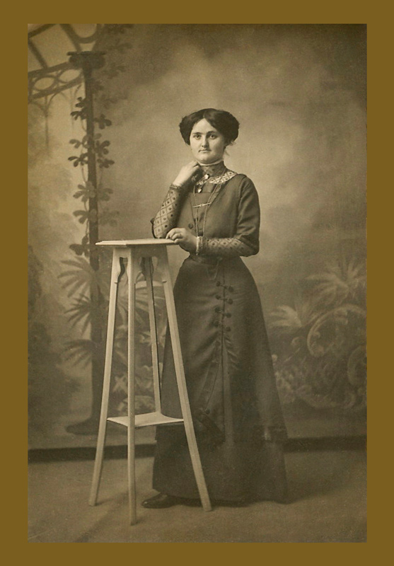 Photographie d'Ernestine vers 1910, posant en robe élégante dans un studio photographique.
